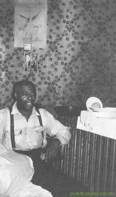 J A M E S   'K O K O M O'   A R N O L D; Kokomo Arnold in his home (4413 South Calumet Avenue) in Chicago, IL, September 1959; source: Jacques Demêtre & Marcel Chauvard: Voyage au Pays du Blues.- Levallois-Perret (CLARB-Soul Bag) 1994, p. 146; photographer: Jacques Demetre