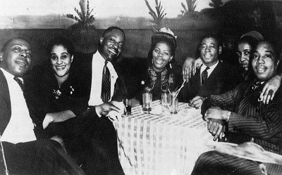 Big Maceo Merriweather, Rose Allen Broonzy, Big Bill Broonzy, Lil Green, 'Jimmy', Lucille Merriweather, drummer Tyrell Dixon, c. late 1940s; source: Harrison 1995, p. 25 ('courtesy Mike Rowe'/Lucy Kate Merriweather); damages cleared up by Stefan Wirz