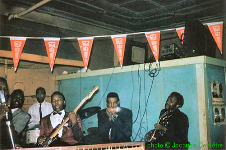 Muddy Waters Band at Smitty's Corner, Chicago, 1959; l to r: Muddy Waters (just visible), Otis Spann, Francis Clay, Andrew Stephens, Little Walter & Pat Hare; source: Juke Blues #23 (Summer 1991), p.11; photographer: Jacques Demêtre