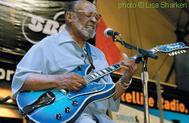 R O B E R T   L O C K W O O D, Jr., playing his custom-built Japanese electric 12-string guitar, built by Moony Omote and Age Sumi from Blues Guitar/Open Natural G Musical Instruments; source: https://www.vintageguitar.com/35513/robert-lockwood-jr-1915-2006/; photographer: Lisa Sharken