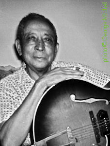 T a m p a   R E D  at his home, 1963; 'Tampa Red no longer played in 1963, but he still loved his guitar. Kept it set up right across the room from where he sat so he could always easily see it. He held it for this photograph I took of him when Big Joe Williams, Michael Bloomfield, and I visited him.' source: 09/28/2020 facebook post by George Mitchell; photographer: George Mitchell