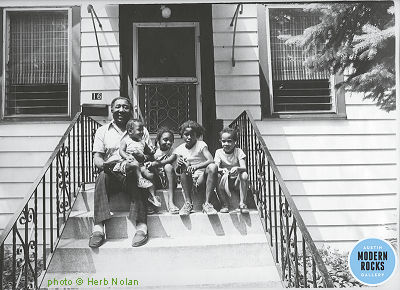 Muddy Waters at his [1974-1983] home, 16 South Adams St. in Westmont, Illinois, 1978; l to r: Muddy Waters, great-granddaughters NaCherrie & Chandra 'Peaches' Cooper, daughter Ros(a)lind [born March 3, 1970] & a friend of theirs, Lisa; source of photo: http://www.modernrocksgallery.com/chicago-jazz-blues-archive-herb-nolan/muddy-waters; photographer: Herb Nolan (Depicted persons identified by Joseph Morganfield on his facebook timeline)