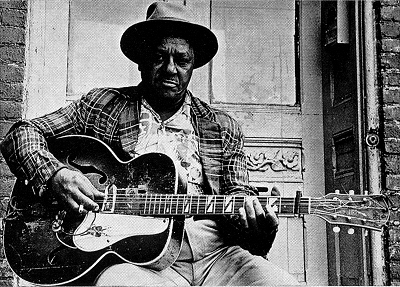 Big Joe Williams playing his nine-string guitar; source: Front cover of 77 LA 12/19; photographer: Ray Flerlage