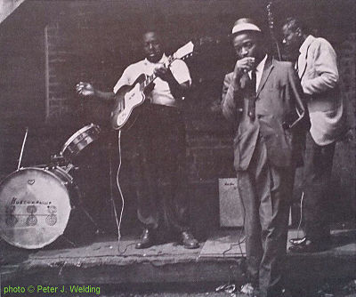 'Huston Phillip''s drum, Johnny Young, B I G   J O H N   W R E N C H E R & Carey Bellat at the corner of 14th and Newberry St., Chicago, IL; source: Back cover of Testament T-2203 (re-release by OJL 19??) 'Modern Chicago Blues'; photographer: Peter J. Welding